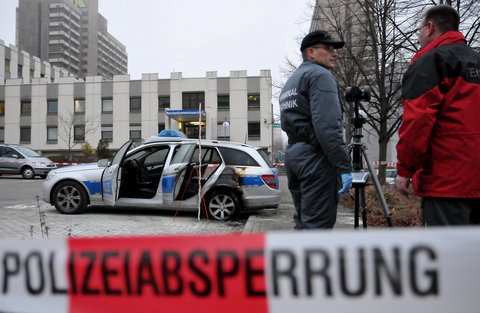 Zwei Kriminaltechniker untersuchen den durch den Brandanschlag beschädigten Streifenwagen vor dem Polizeirevier in Neustadt