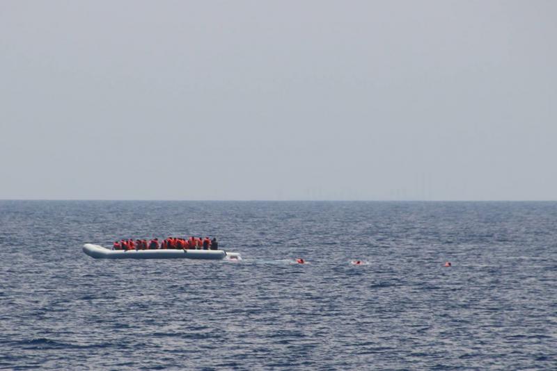 Menschen die mit Schwimmwesten aus dem Schlauchboot springen um zum nächsten Schiff zu gelangen