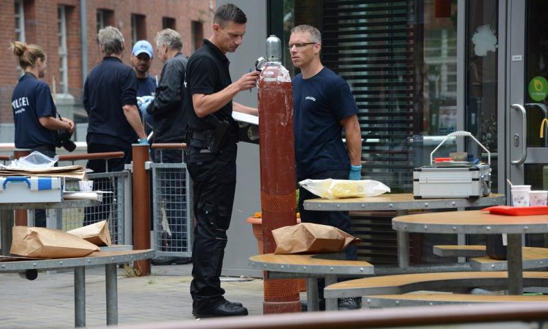 Ein Sprengstoff-Experte inspiziert die Gasflasche vor der Filiale mit einer Lupe (Foto: Timo Beurich)