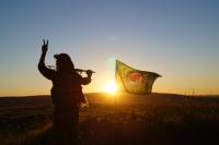 YPG-Kämpfer vor Rojava-Fahne nach der Befreiung Kobanes im Januar 2015 (Bildlizenz: CC BY-NC-SA)