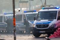 Polizeibeamte gehen hinter ihren Fahrzeugen auf der Karl-Liebknecht-Straße in Deckung nachdem sie mit Steinen, Rauchkörpern und andere Gegenständen beworfen worden waren