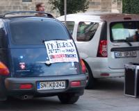 Auf dem Plakat steht: "Frieden jetzt und immer – Revolution – Und einen schnellen sanften Tod allen Politikern und Spekulanten"; Im Hintergrund Konstantin Stößel, Anmelder der strafwütigen Friedensaktivisten