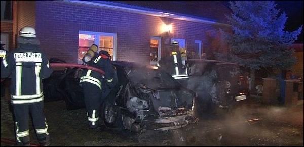 Feuerwehrmänner löschen die in Brand gesteckten Fahrzeuge vor einem Eigenheim im Magdeburger Stadtteil Ottersleben. Ein Fahrzeug gehört dem ehemaligen Mitglied im NPD-Bundesvorstand, Andy Knape.