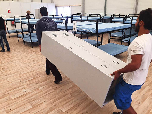 Asylbewerber aus Mannheim bauen die letzten Betten auf und tragen Schränke.