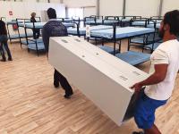 Asylbewerber aus Mannheim bauen die letzten Betten auf und tragen Schränke.