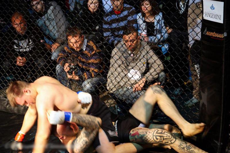 Vít Mrákota in Rome in 2013. White Rex logo on the knee and Skrewdriver on the shin are not his only Nazi tattoos. You can also see a part of the Czech audience behind the cage.