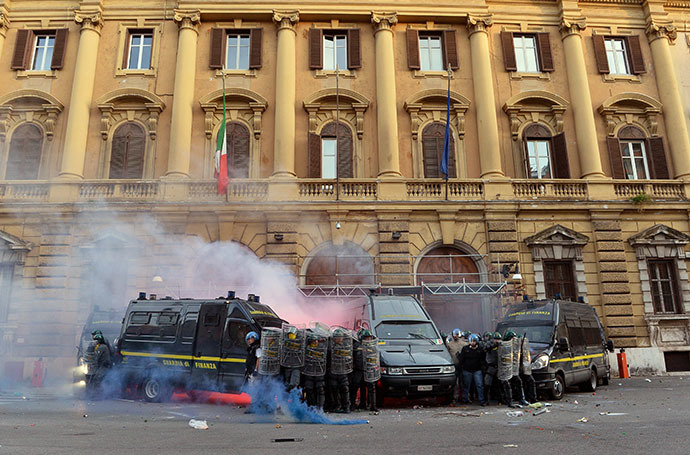 Members of the Guardia di Finanza protect themselves as they stand in front of the Economy minister during clashes on the sidelines of an anti-austerity protest on October 19, 2013 in Rome.