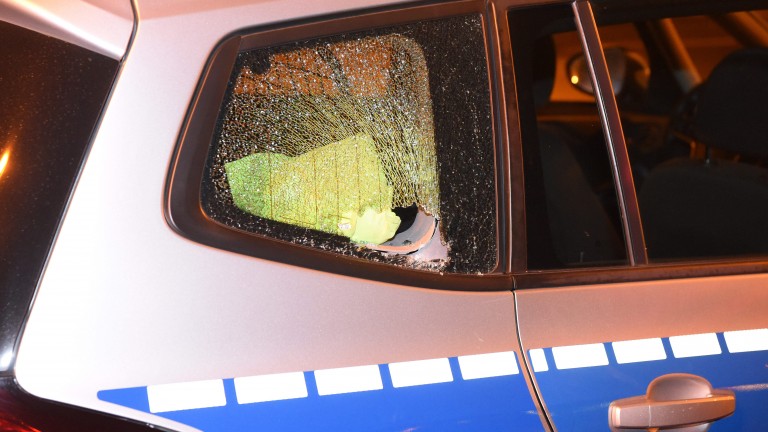 Eine eingeworfene Scheibe an einem der Polizeiautos