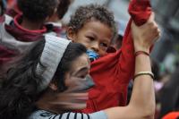 Auf der Zwischenkundgebung tanzt eine Aktivistin mit einem Kleinkind zu den Sambarhythmen